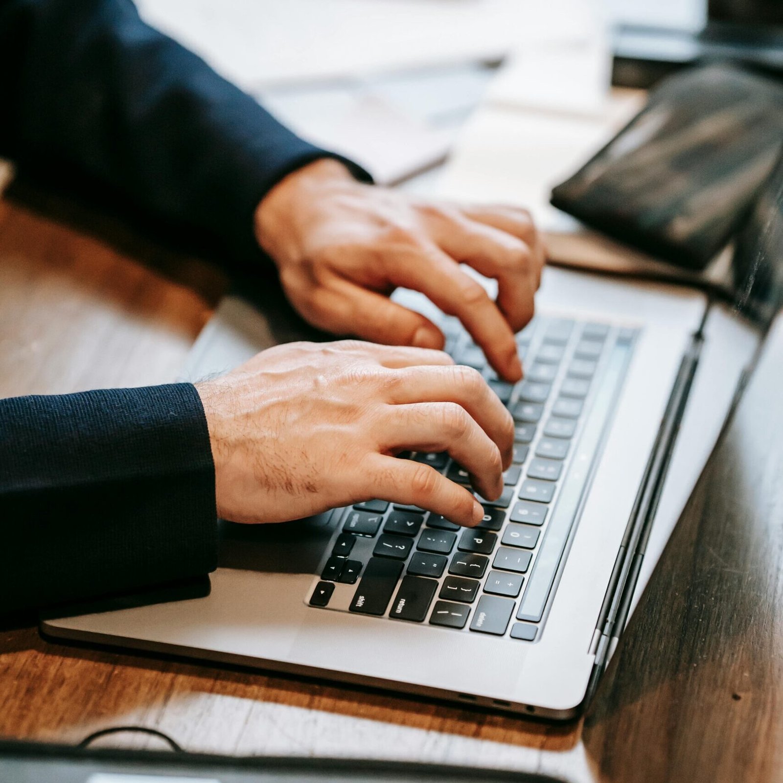 Close-up of a professional typing on a laptop indoors, highlighting remote work and technology.